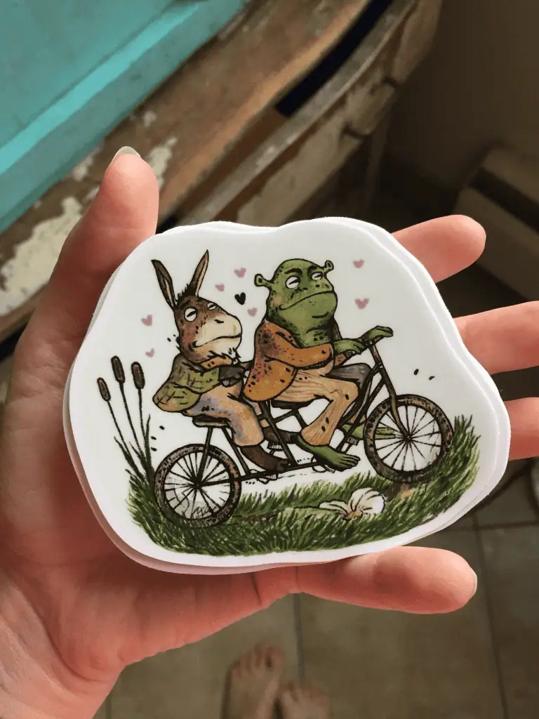 Cute animal sticker with a rabbit and frog riding a bicycle.